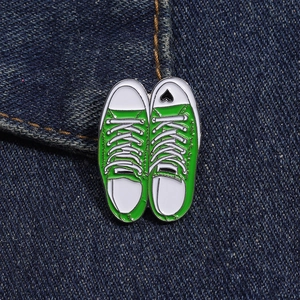 Detailed close-up of green canvas shoe enamel pins on blue denim fabric
