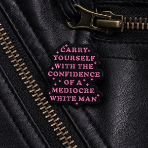 Detailed macro of enamel pin with quote on black leather jacket showing texture