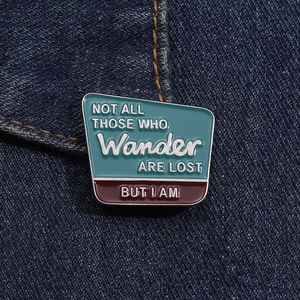 Détail d'une broche émaillée avec citation humoristique sur fond de tissu denim