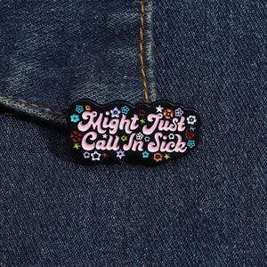 Detail of Might Just Call In Sick enamel pin with pink text and floral accents