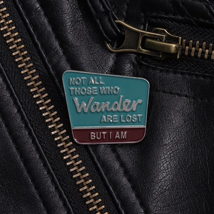 Détail d'une broche émaillée avec citation sur une veste en cuir noir et zip métallique