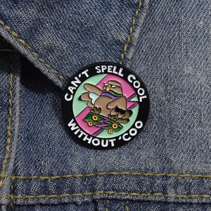 Détail du pin's pigeon skateboard sur denim avec texte CAN'T SPELL COOL WITHOUT COO
