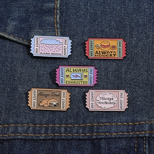Detailed close-up of set of five funny cartoon enamel pins on blue denim fabric background