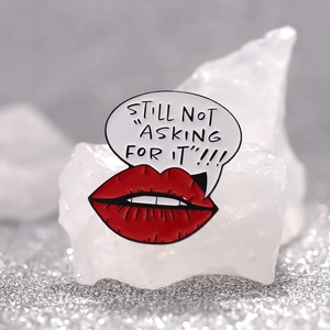 Detailed macro view of an enamel red lips brooch with a creative text speech bubble design