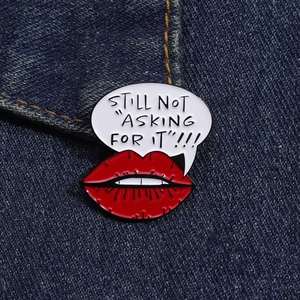 Macro detail of 'STILL NOT ASKING FOR IT' enamel pin with red lips on denim