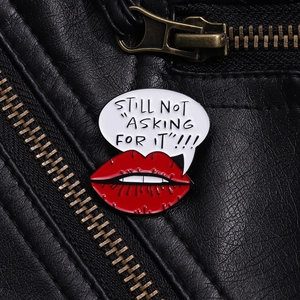 Detailed macro view of red lip enamel brooch with slogan on a black leather jacket