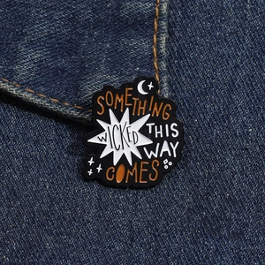 Detail of Something Wicked This Way Comes enamel pin on blue denim jacket fabric