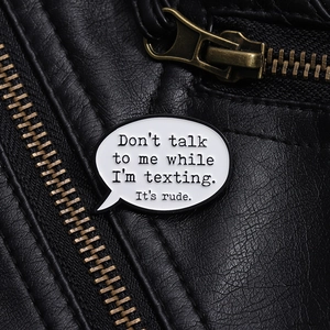 Minimalist speech bubble enamel pin with humorous text on black leather jacket