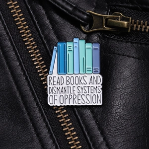 Detail of creative enamel book pin with slogan on black leather jacket texture