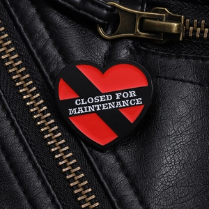 Détail de l'épingle en émail cœur rouge avec texte sur une veste en cuir noir