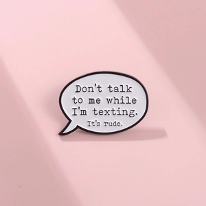Détail du pin's émaillé en bulle avec texte humoristique sur un fond rose uni