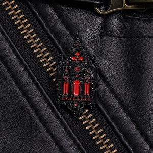 Close-up of Gothic castle window brooch with red enamel on a black leather jacket