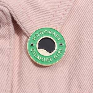 Gros plan du pin's émaillé Honorary Gilmore Girl sur une veste en jean rose vif