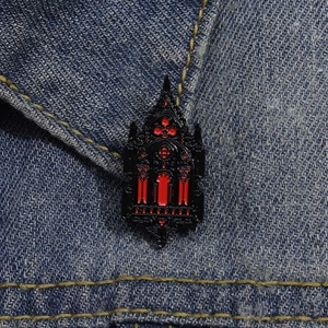 Detail of gothic church window enamel brooch with red paint on blue denim jacket