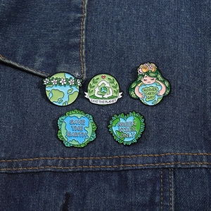 Lot de cinq pin's émaillés écologiques aux slogans terrestres sur tissu en jean