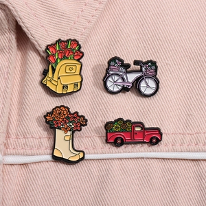 Gros plan de quatre épingles en émail floral avec camion de fleurs sur denim rose