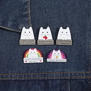 Set of 5 cartoon cat enamel pins with humorous slogans on dark blue denim fabric