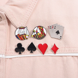 Detail of seven poker-themed enamel pins displayed on pink denim fabric material