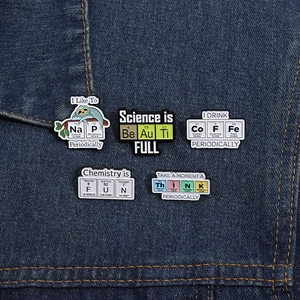 Detailed view of science-themed enamel pins featuring chemical elements on denim fabric