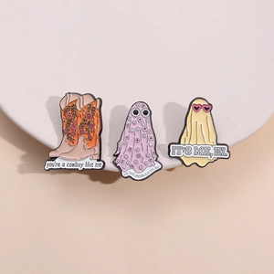 Detailed macro view of Taylor-inspired enamel pins featuring cowboy boots and ghost motifs