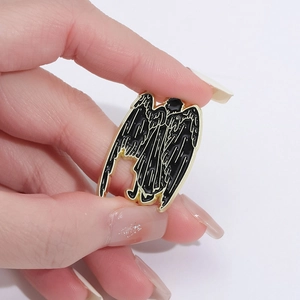 Good Omens inspired black angel enamel pin with gold metal outlines and feather detail