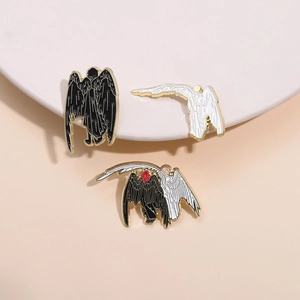 Detail of Good Omens inspired black and white wing enamel pins with gold plating