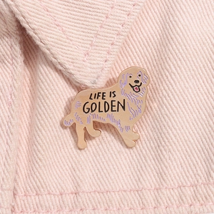 Vue macro d'une épingle Golden Retriever en émail avec gravure LIFE IS GOLDEN sur tissu