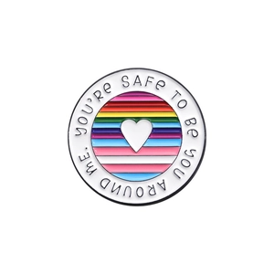 Rainbow circular enamel pin with You're Safe To Be You Around Me text and white heart