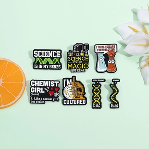 Detailed view of six colorful enamel science pins featuring DNA and microscope motifs