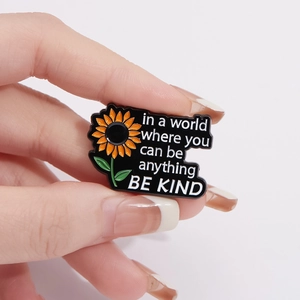 Broche tournesol en émail avec citation inspirante Be Kind sur un fond noir mat