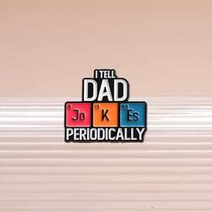 Funny Dad Jokes enamel pin with periodic table design on a textured display stand