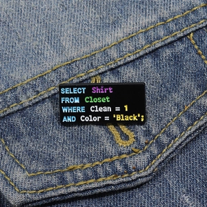 Gros plan d'un badge en émail avec code SQL noir fixé sur une veste en jean bleue