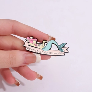 Pin's en émail sirène de dessin animé avec cheveux roses et ruban tenu dans la main