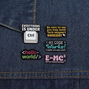 Detailed close-up of geek and programmer enamel pins displayed on denim fabric texture