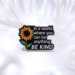Pin's tournesol en émail avec citation Be Kind sur fond en métal noir brillant