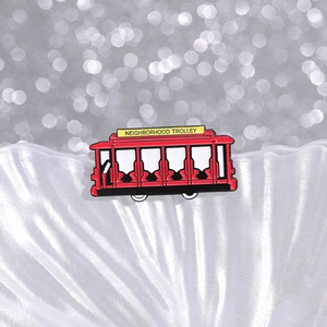 Detailed close-up of a red vintage alloy trolley brooch on a white decorative tray