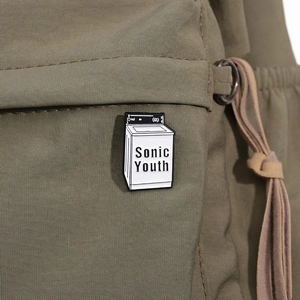 Dettaglio della spilla smaltata Sonic Youth attaccata a una tracolla in tela verde