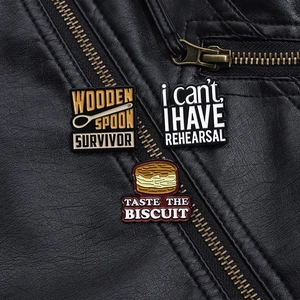 Detailed macro of three enamel pins featuring creative biscuit and phrase designs