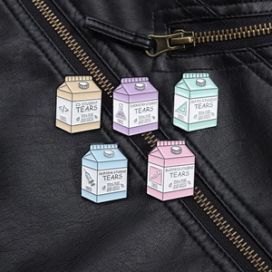 Close-up of five cartoon milk box enamel pins attached to a black leather jacket