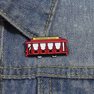 Detailed close-up of a red Neighborhood Trolley enamel pin on a blue denim jacket collar