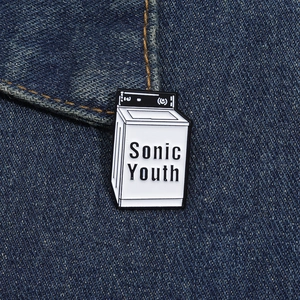 Dettaglio della spilla smaltata lavatrice Sonic Youth su un tessuto di jeans blu