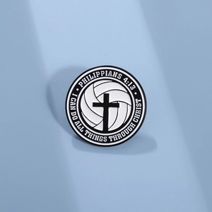 Close-up of circular enamel pin featuring cross volleyball design and scripture text