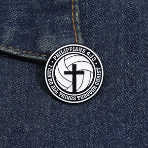 Detail of cross and volleyball enamel pin with Bible verse on blue denim fabric