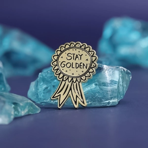 Insigne en émail doré STAY GOLDEN avec étoiles sur un support en cristal bleu