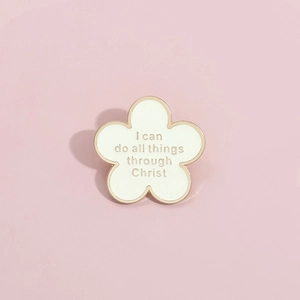 Broche fleur en émail blanc avec bords dorés et citation religieuse sur fond rose