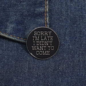 Détail d'une broche ronde en émail avec slogan sur denim montrant la texture métal