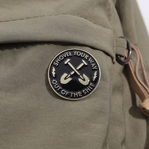 Macro detail of enamel lapel pin with shovel design pinned on a canvas backpack