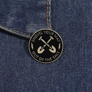 Detailed view of a round enamel shovel badge pinned on dark blue denim fabric