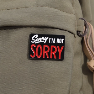 Détail du pin's émaillé Sorry I'm Not Sorry sur un sac en toile vert armée