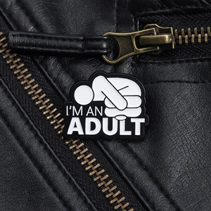 Détail du badge en métal avec figurine blanche sur une veste en cuir noir texturé